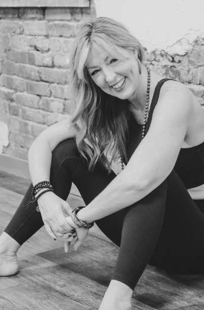 A woman sitting on the ground smiling for a picture.