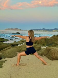 A woman is doing yoga on the beach